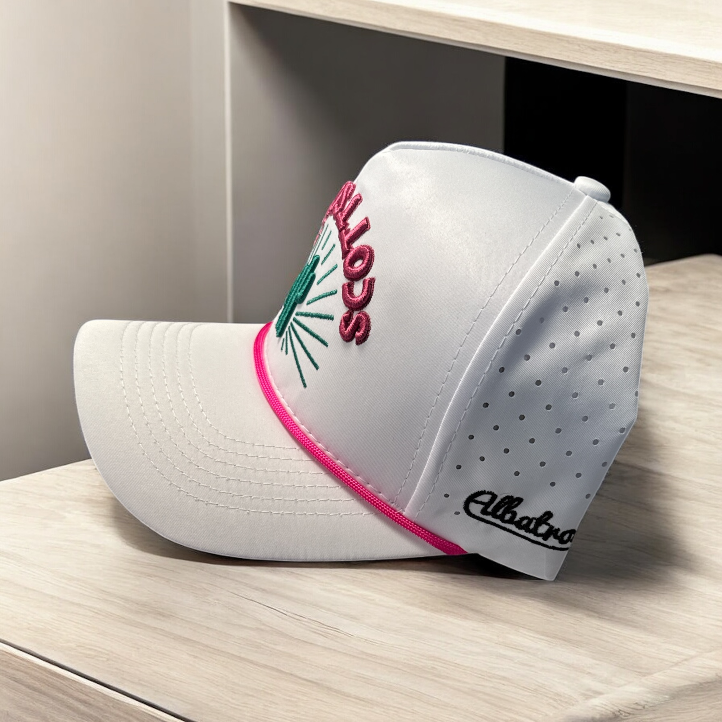 White cap with pink and green accents on a wooden surface