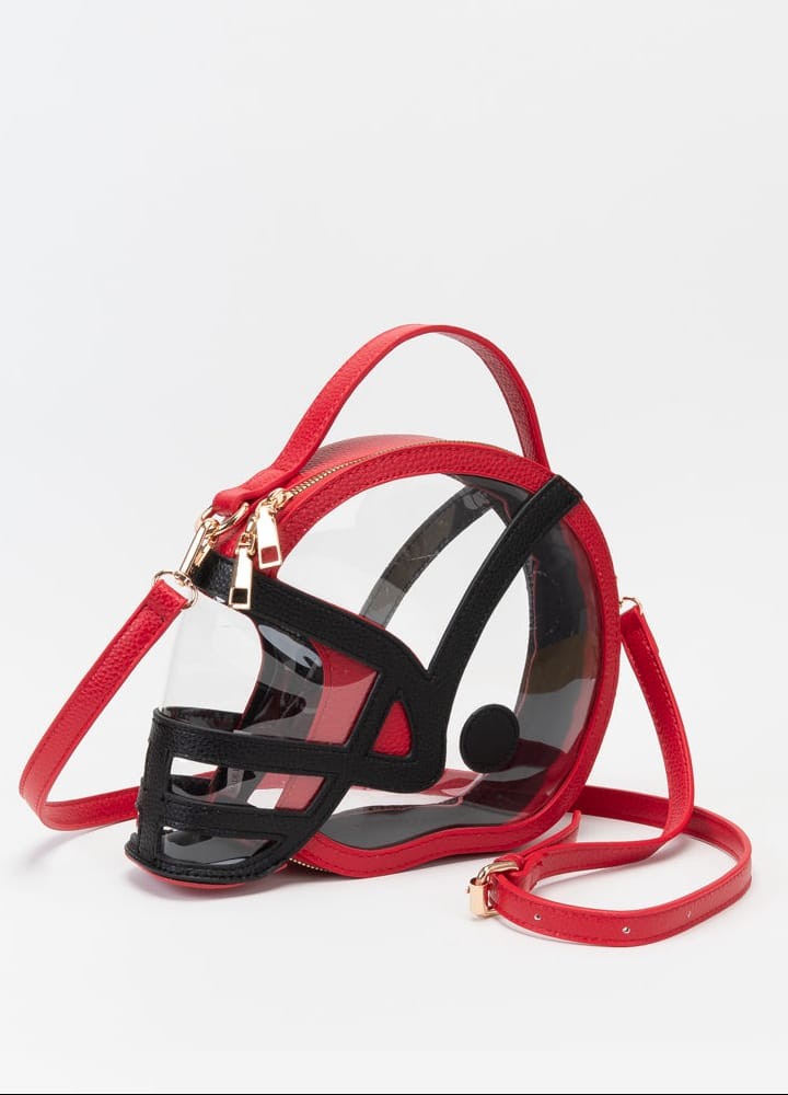 Clear football helmet-shaped crossbody bag with red trim, a black face mask, gold hardware and an adjustable red strap.