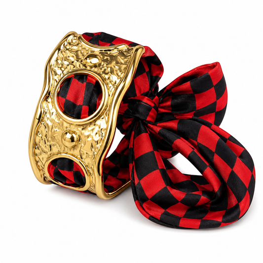Gold-tone textured stainless steel cuff bracelet with a red and black checkered scarf woven through and tied into a statement bow.