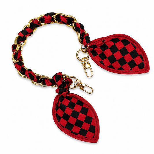 Red and black checkered scarf woven through a gold-tone chain purse strap with swivel clasps and decorative scarf ends.
