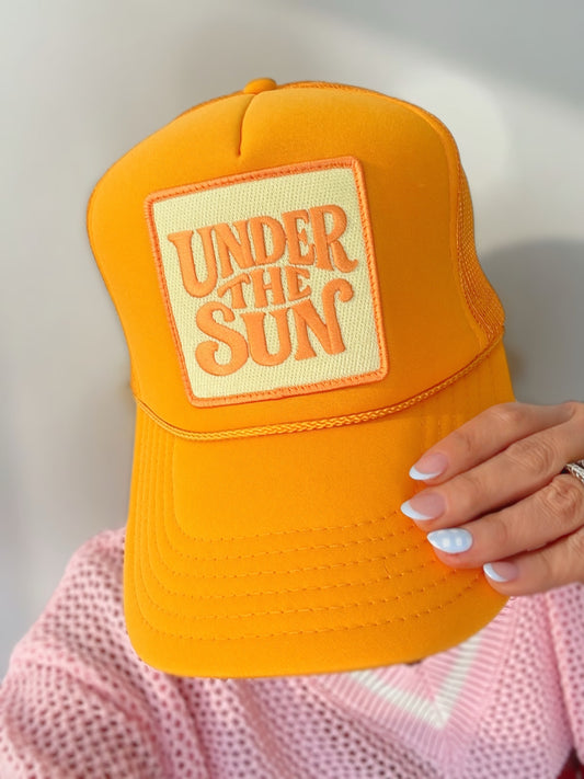 Bright yellow retro trucker hat featuring an embroidered "Under The Sun" patch with breathable mesh back and adjustable snapback design.