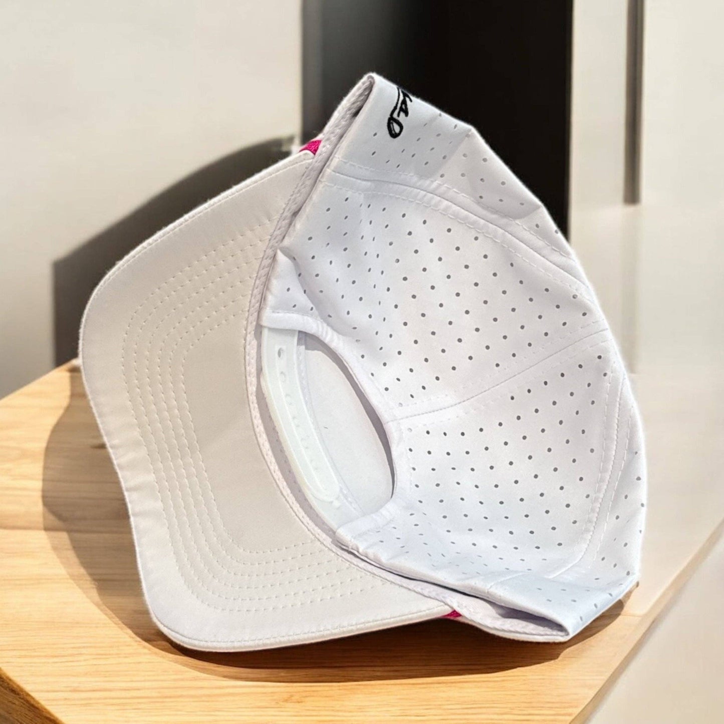 White perforated face shield on a wooden surface with a neutral background