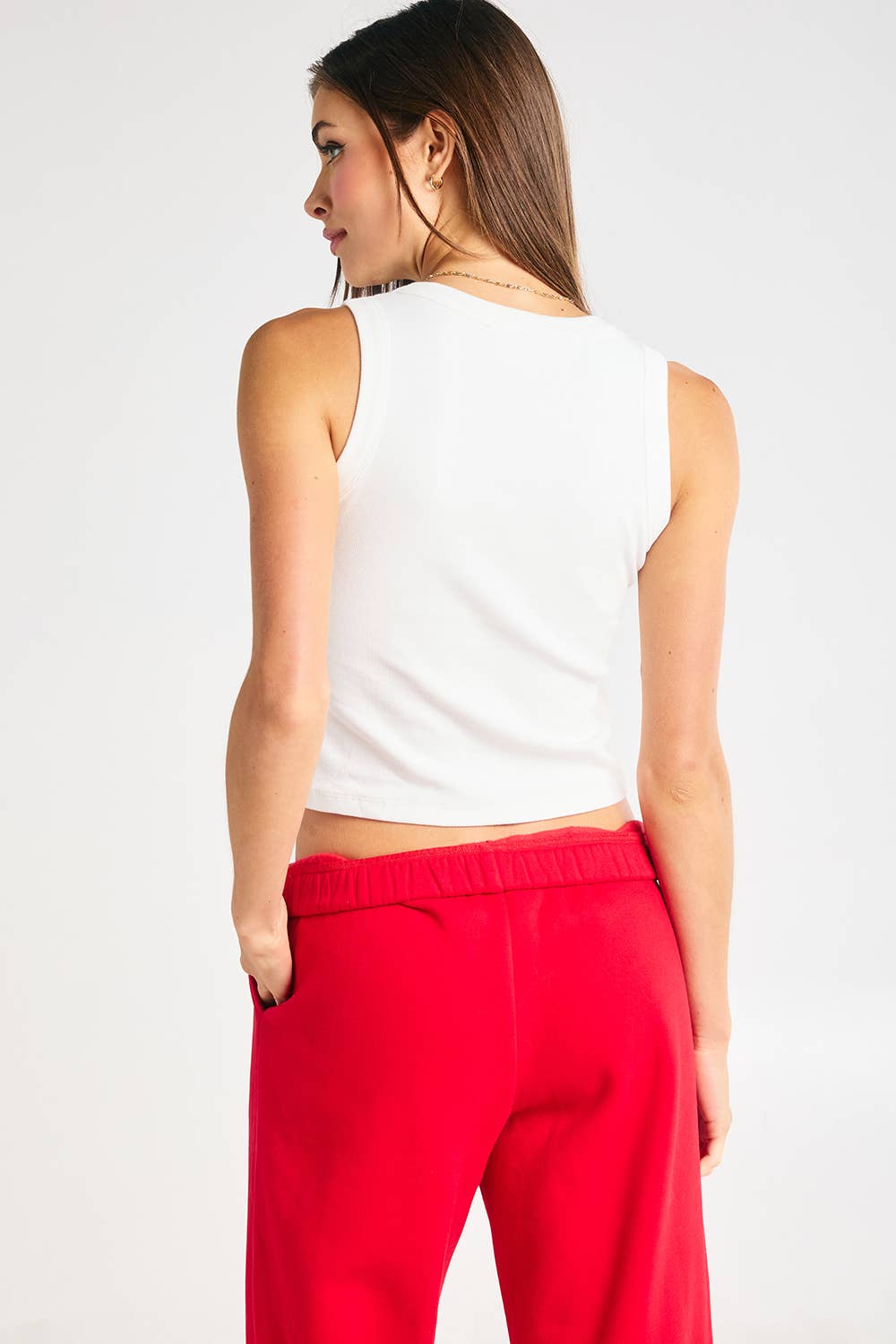 Woman wearing a fitted white ribbed tank top with red cursive “georgia” embroidery.