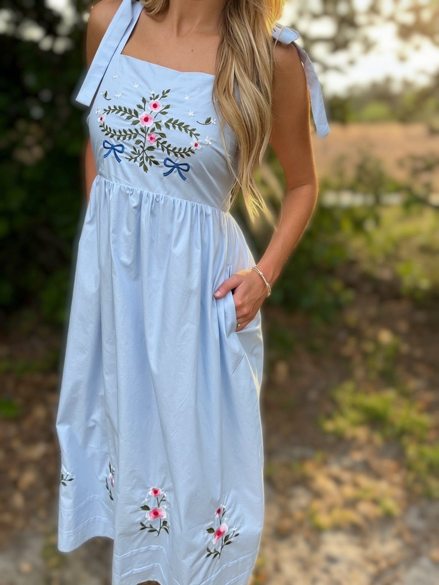 Light blue dress with floral embroidery worn by a person outdoors.
