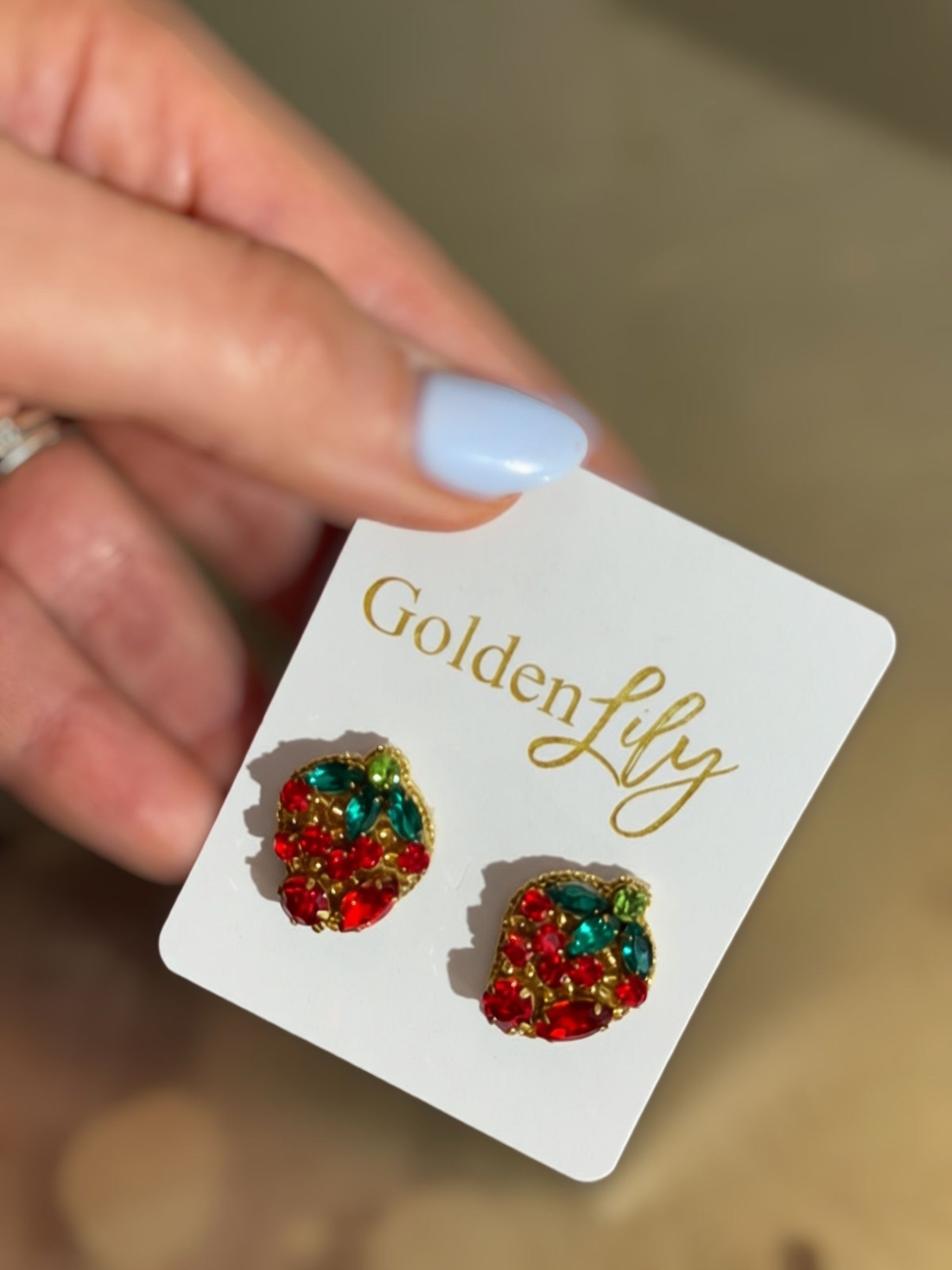 Red and green rhinestone strawberry statement earrings with crystal leaf accents and gold-tone trim displayed on jewelry cards.