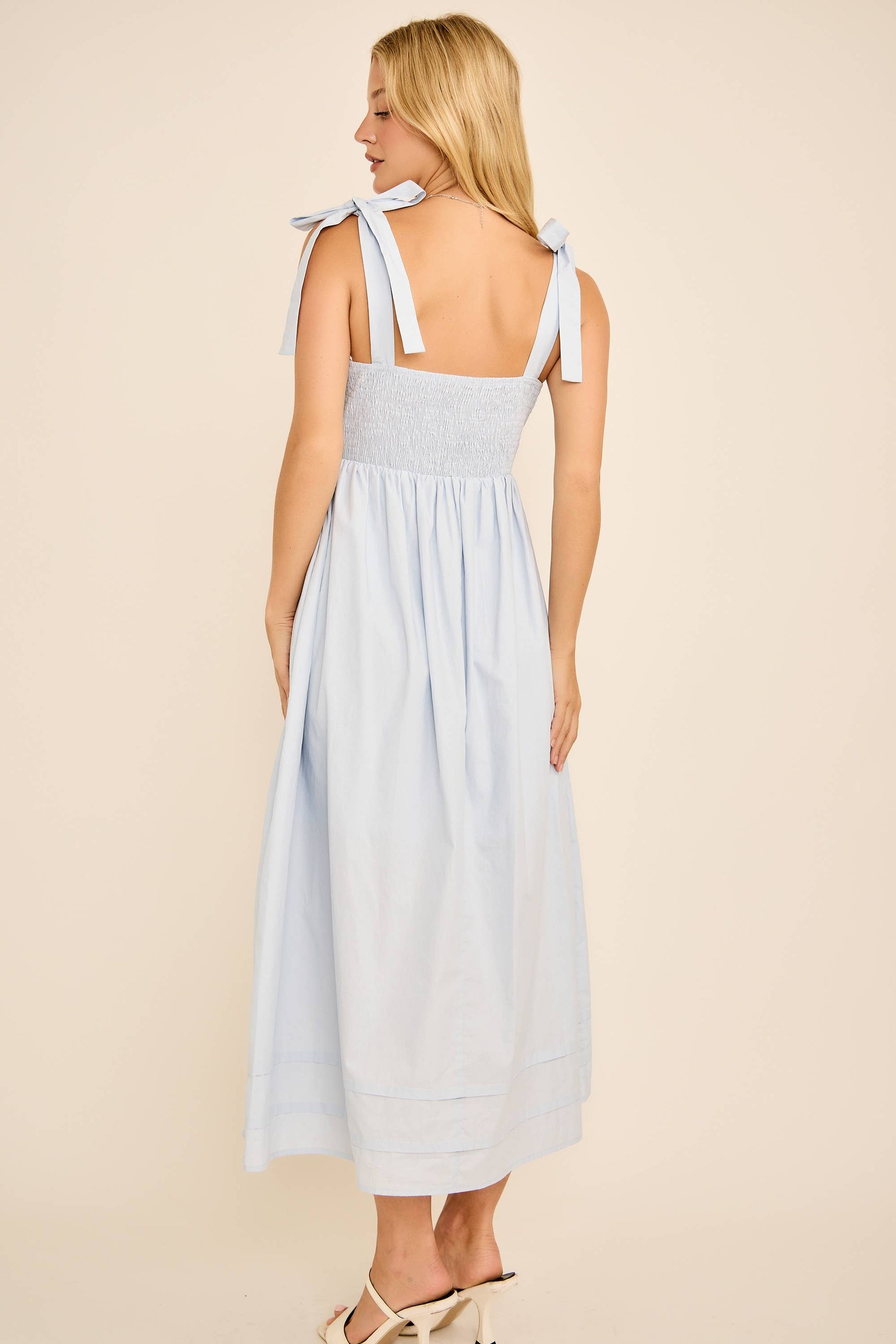 Woman wearing a light blue dress with thin straps on a beige background