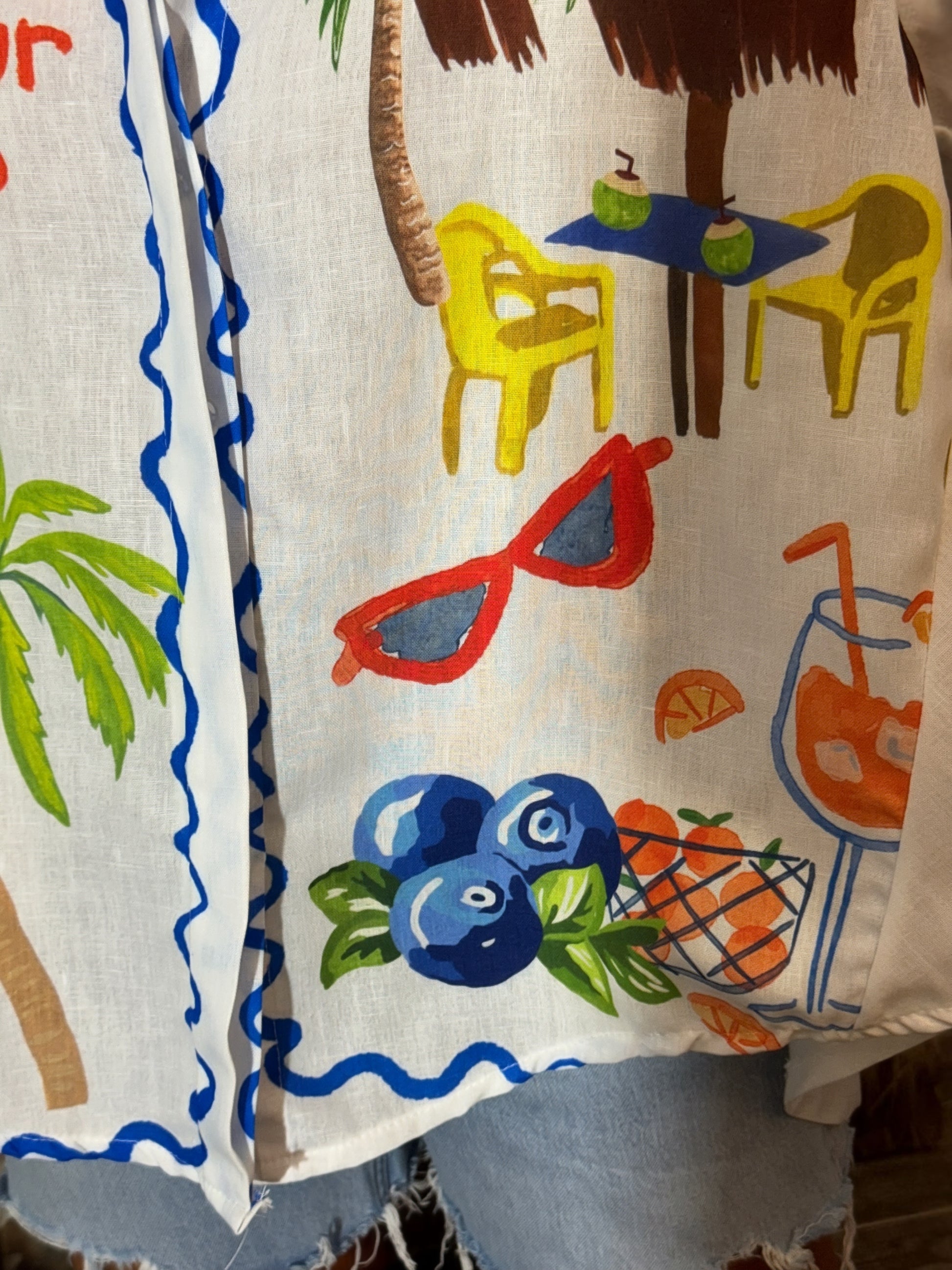 White Italian button-down resort shirt featuring colorful palm trees, citrus artwork, blueberries, and "Put a Little Spritz in Your Step" graphic.