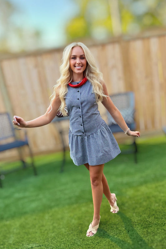 Woman wearing the Sienna black and white gingham sleeveless mini dress with a button-front bodice and gathered drop-waist skirt