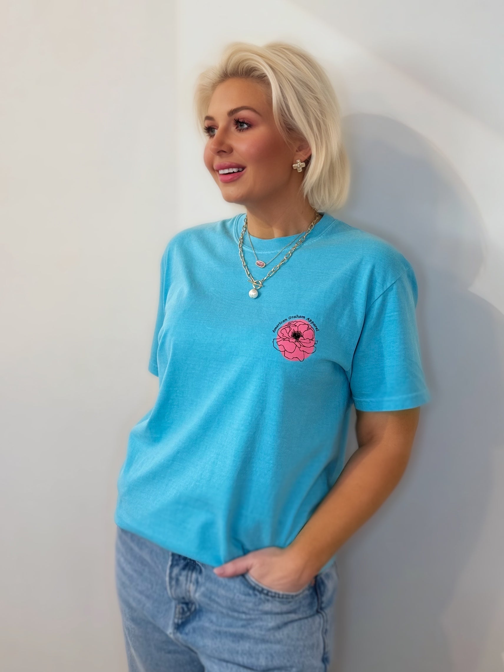 Woman wearing a blue t-shirt with a pink flower design against a white background