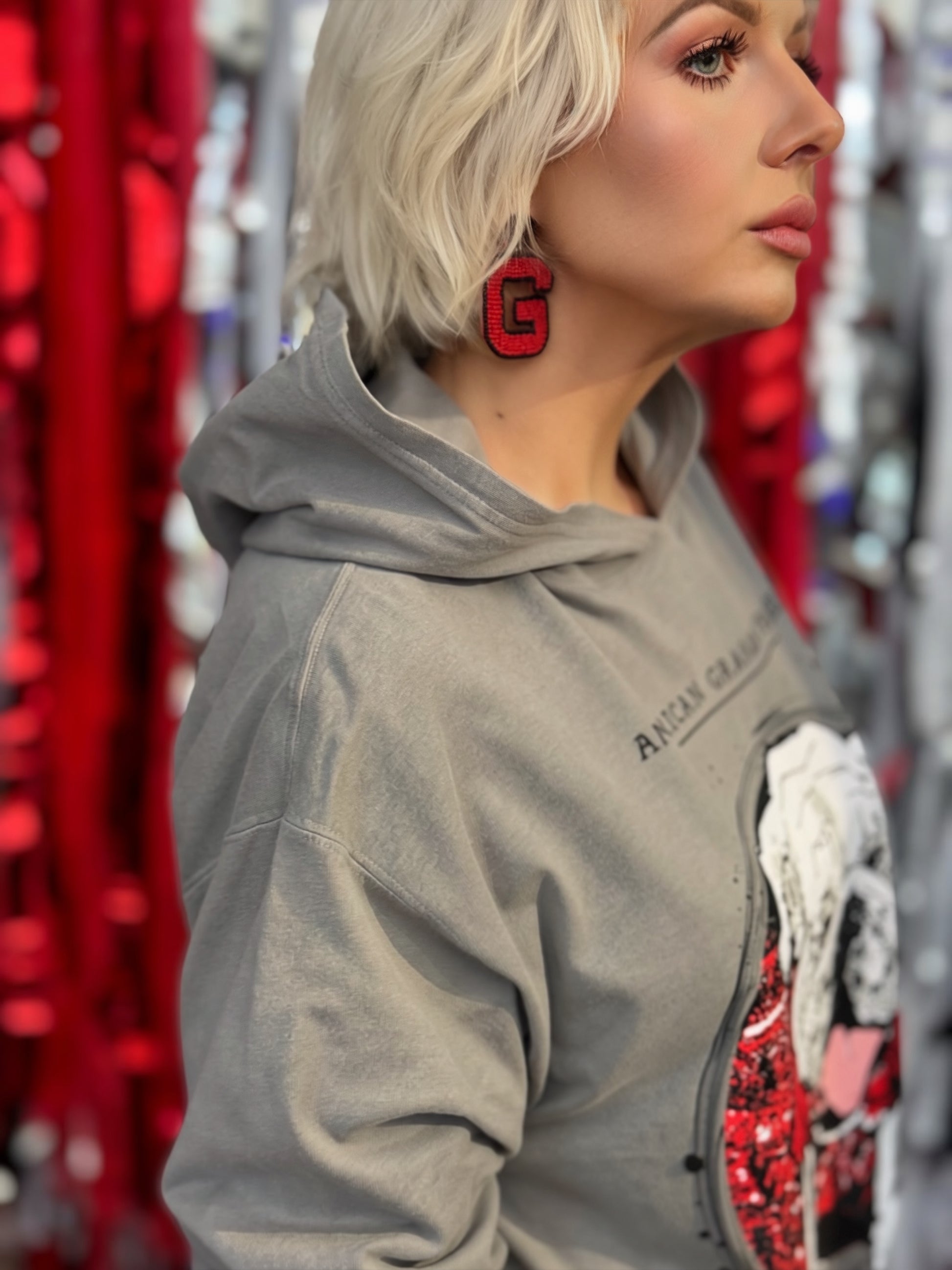 A person wearing a gray hooded long sleeve t-shirt with a large graphic print of a bulldog wearing a red bandana, with the text 'AMERICAN GRAHAM APPAREL' and 'The Classic City We Blood Red & Black' on the front.