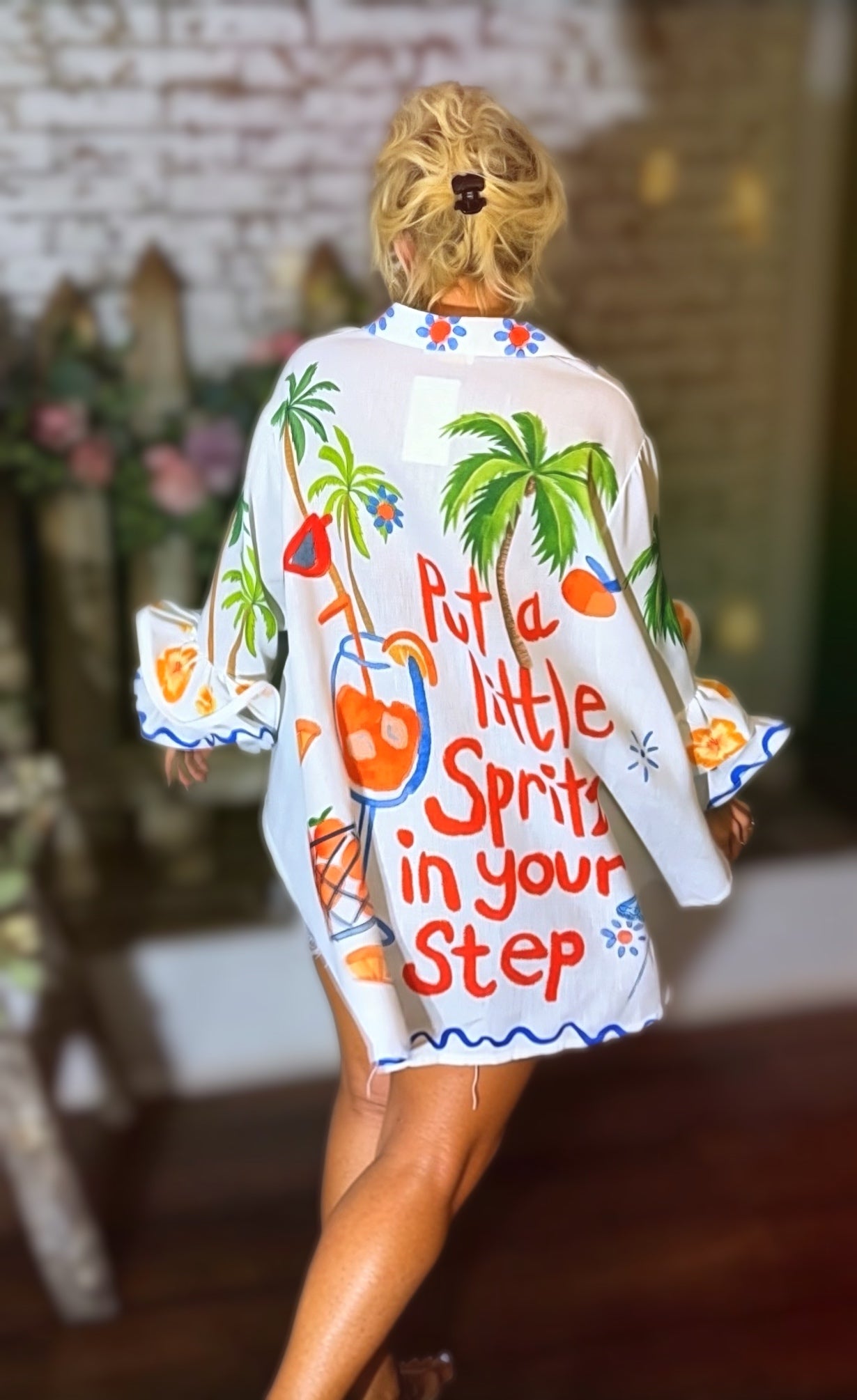 White Italian button-down resort shirt featuring colorful palm trees, citrus artwork, blueberries, and "Put a Little Spritz in Your Step" graphic.