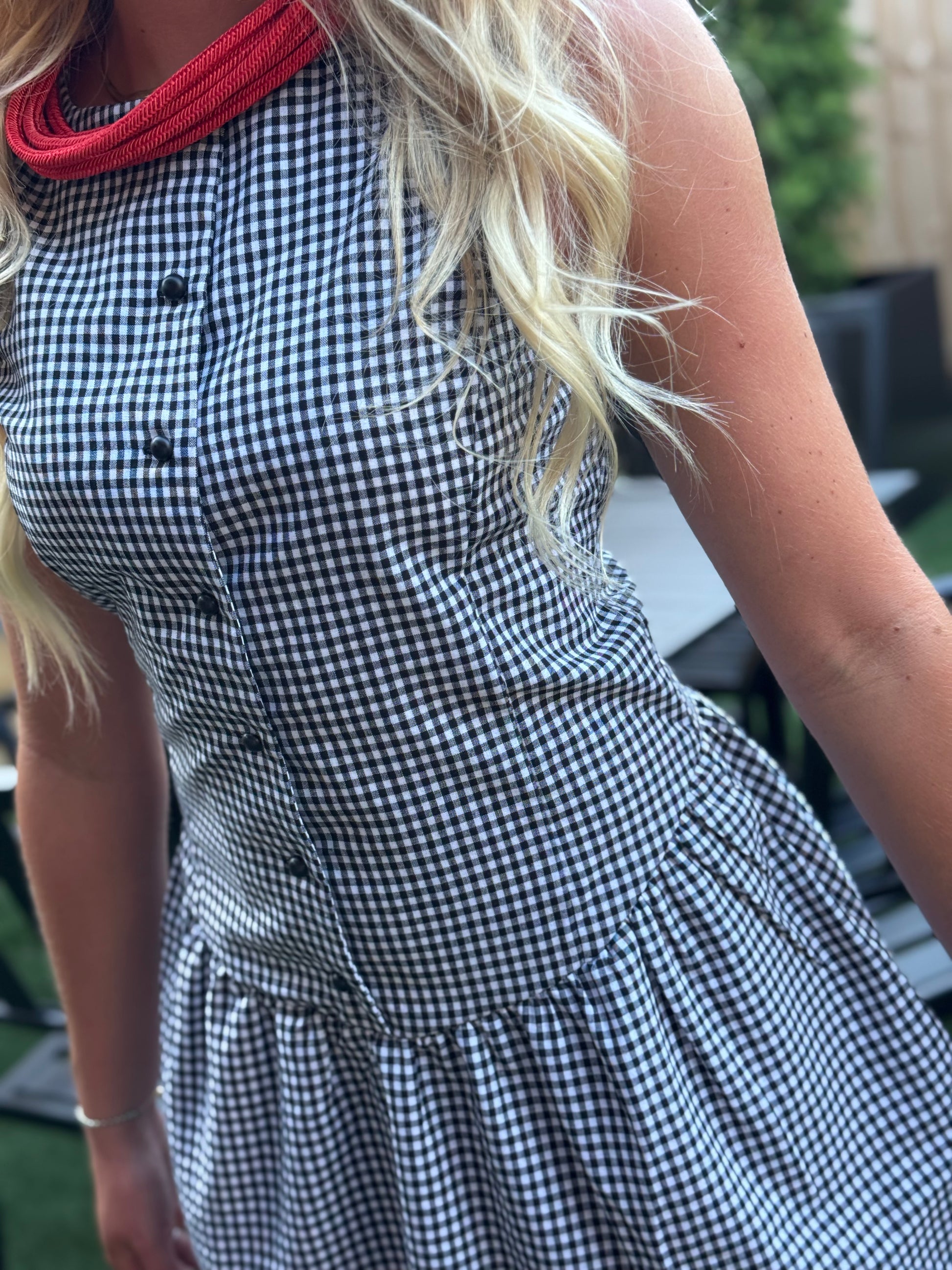 Woman wearing the Sienna black and white gingham sleeveless mini dress with a button-front bodice and gathered drop-waist skirt
