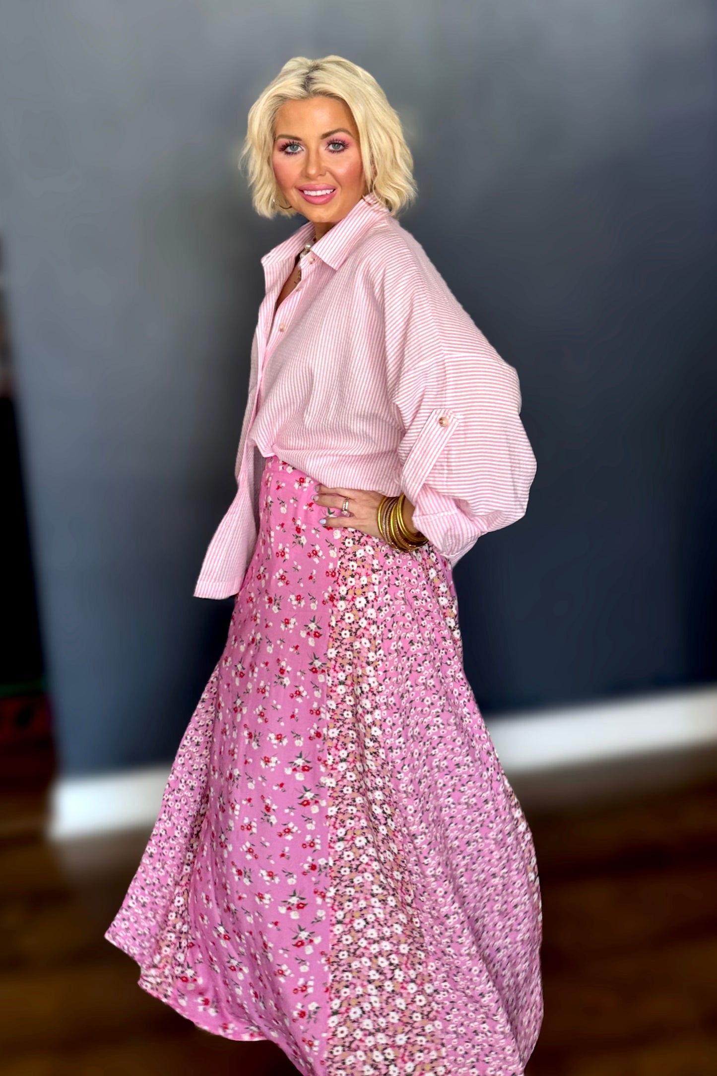 Woman wearing a pink outfit with a patterned skirt against a plain background