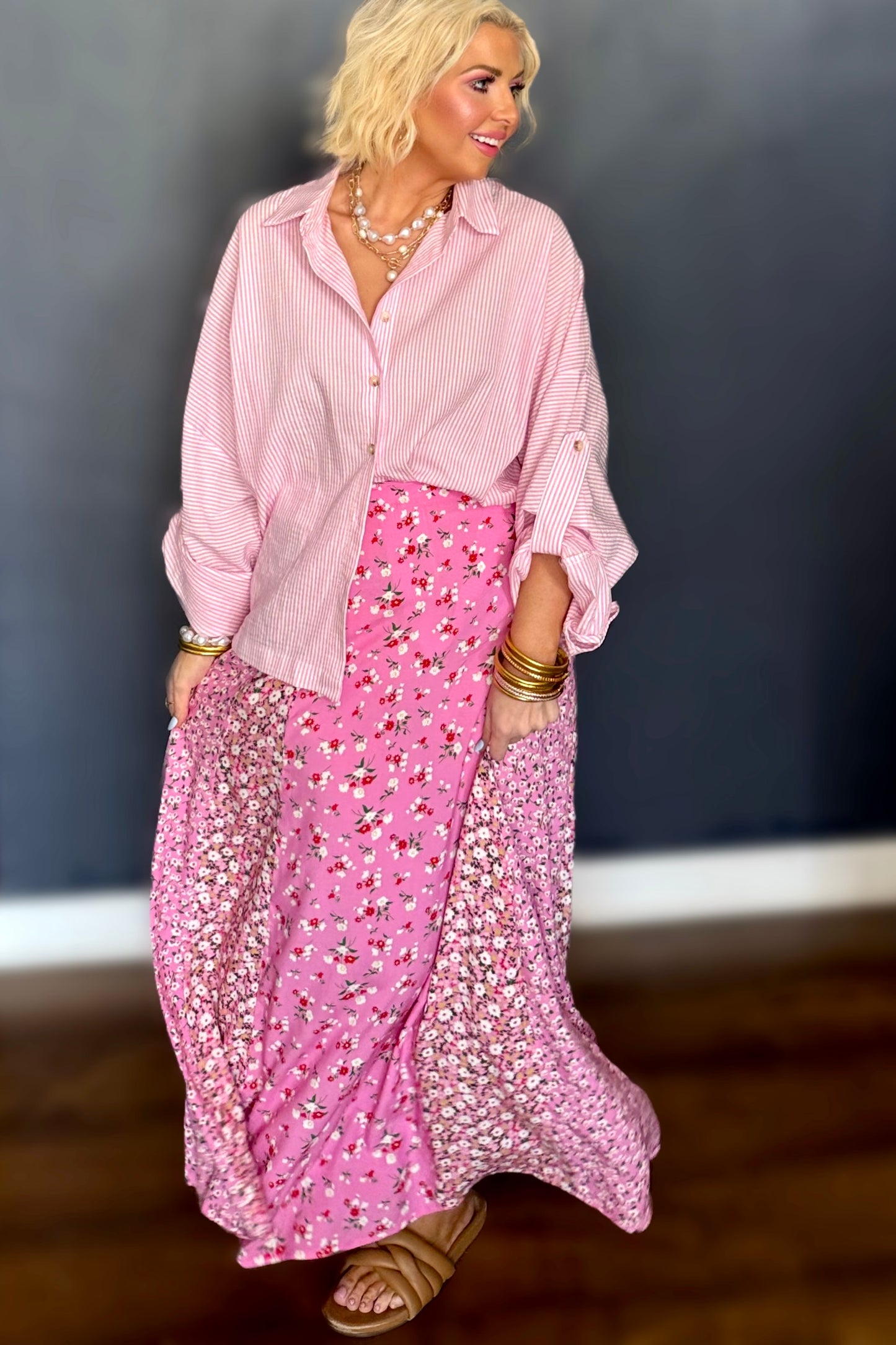 Woman wearing a pink outfit with a floral skirt against a dark background