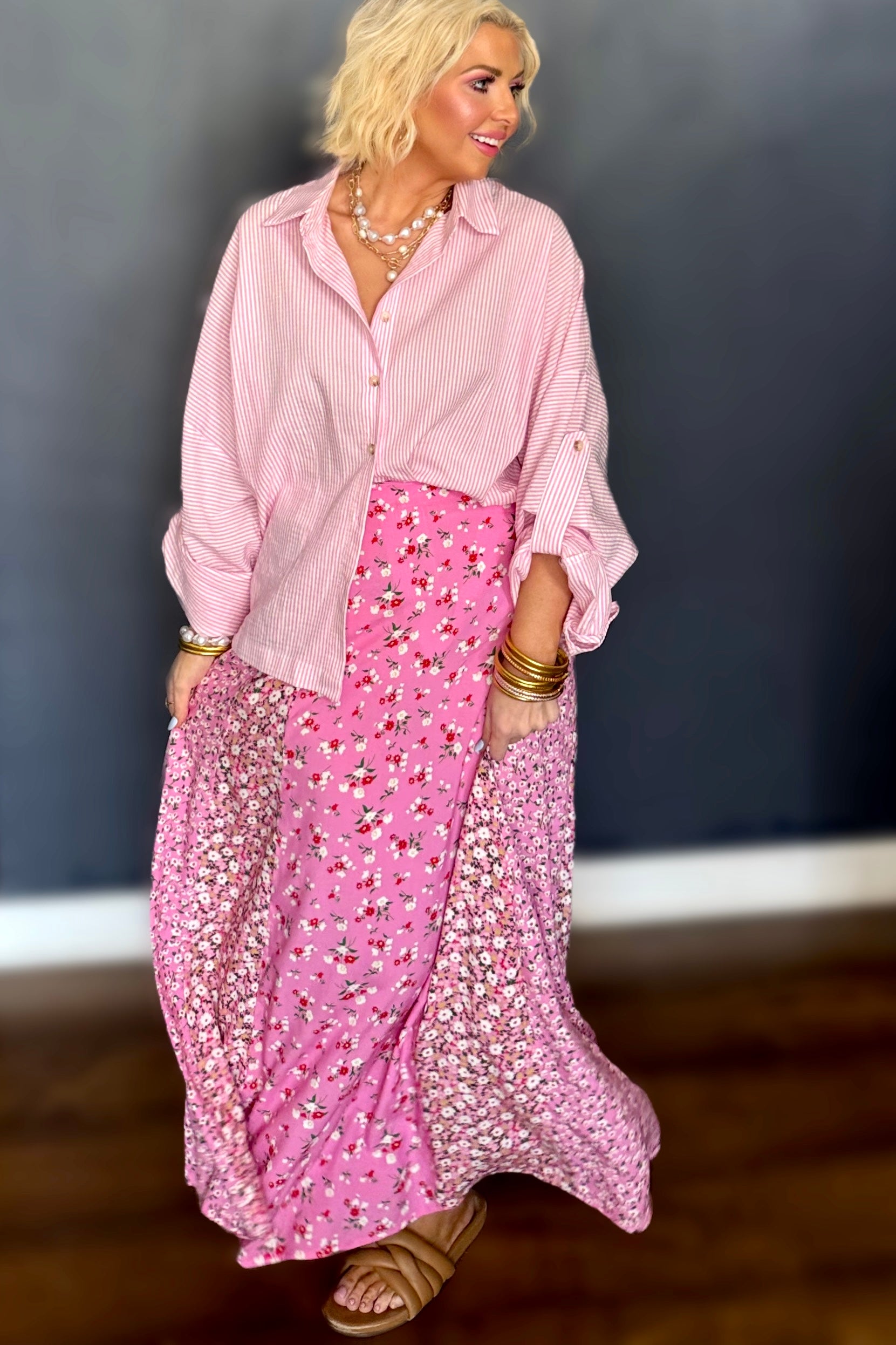 Woman wearing a pink outfit with a floral skirt against a dark background