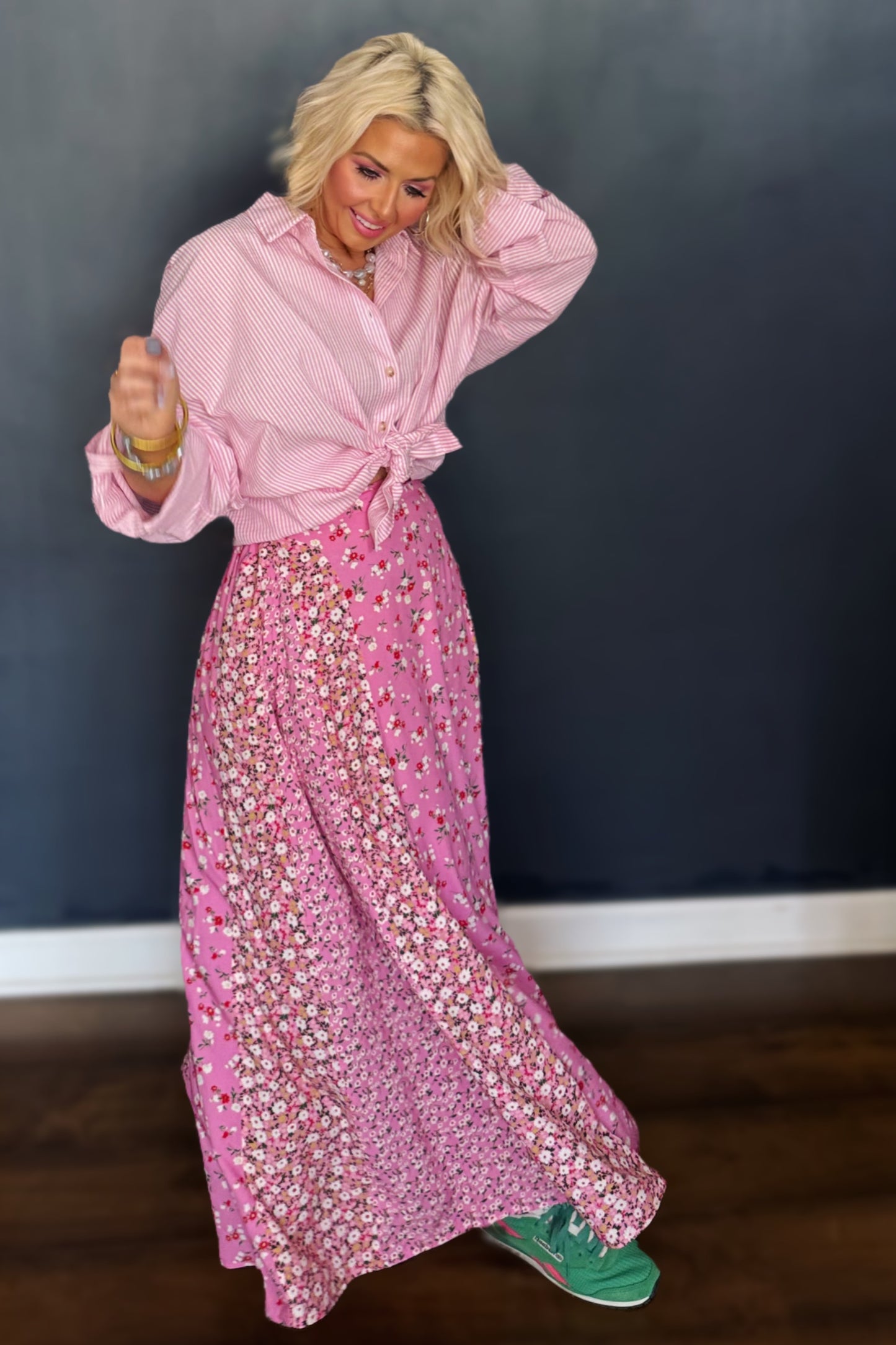 Woman in a pink outfit with a floral skirt against a dark background