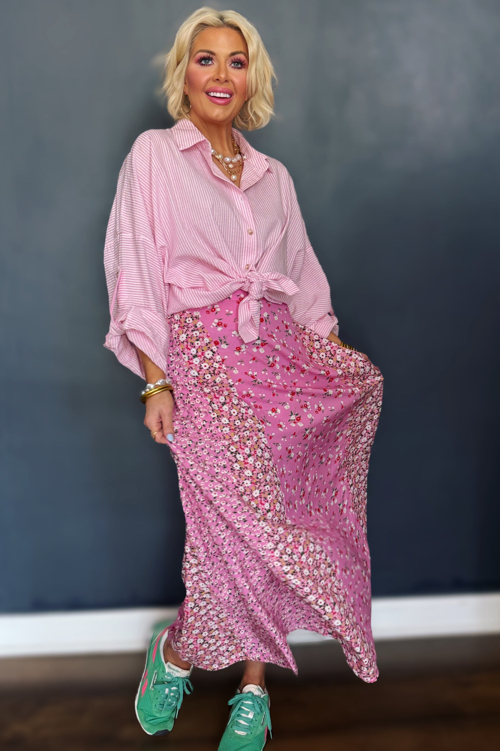 Woman wearing a pink outfit with a floral skirt against a dark background