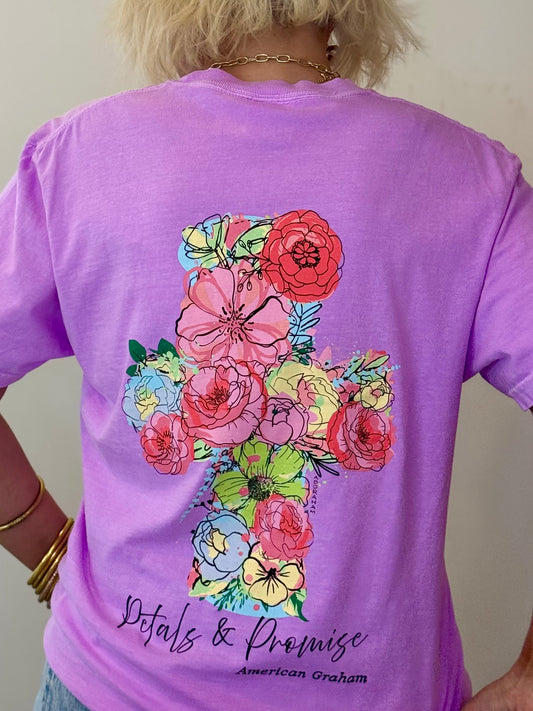 Purple t-shirt with colorful floral design on the back, worn by a person.