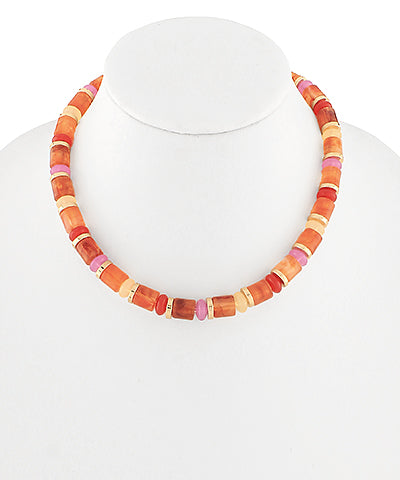 Short beaded choker necklace with orange, coral, peach, and pink resin beads and gold-tone spacers on a white necklace display.