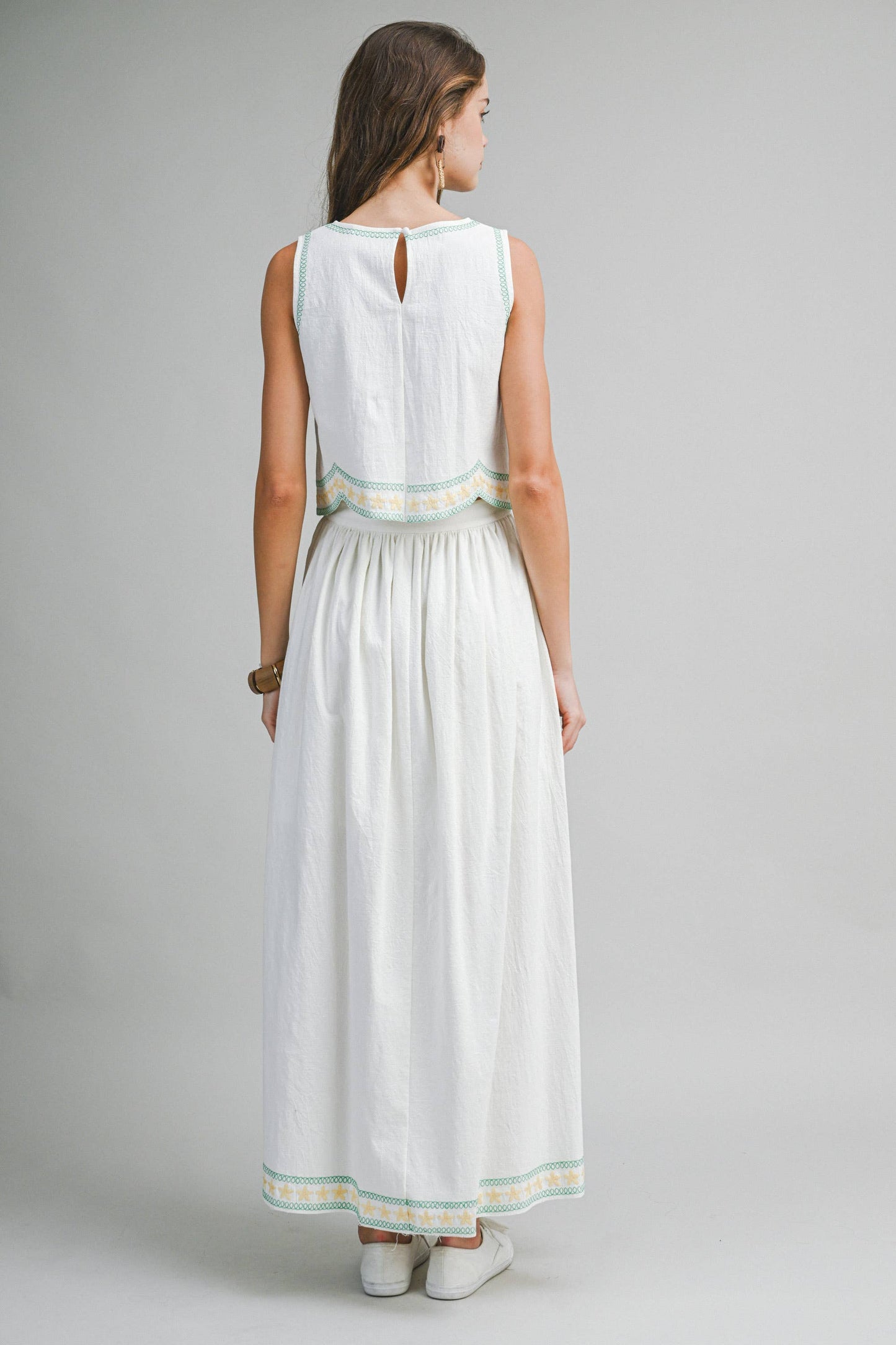Woman wearing a white dress with green trim on a gray background