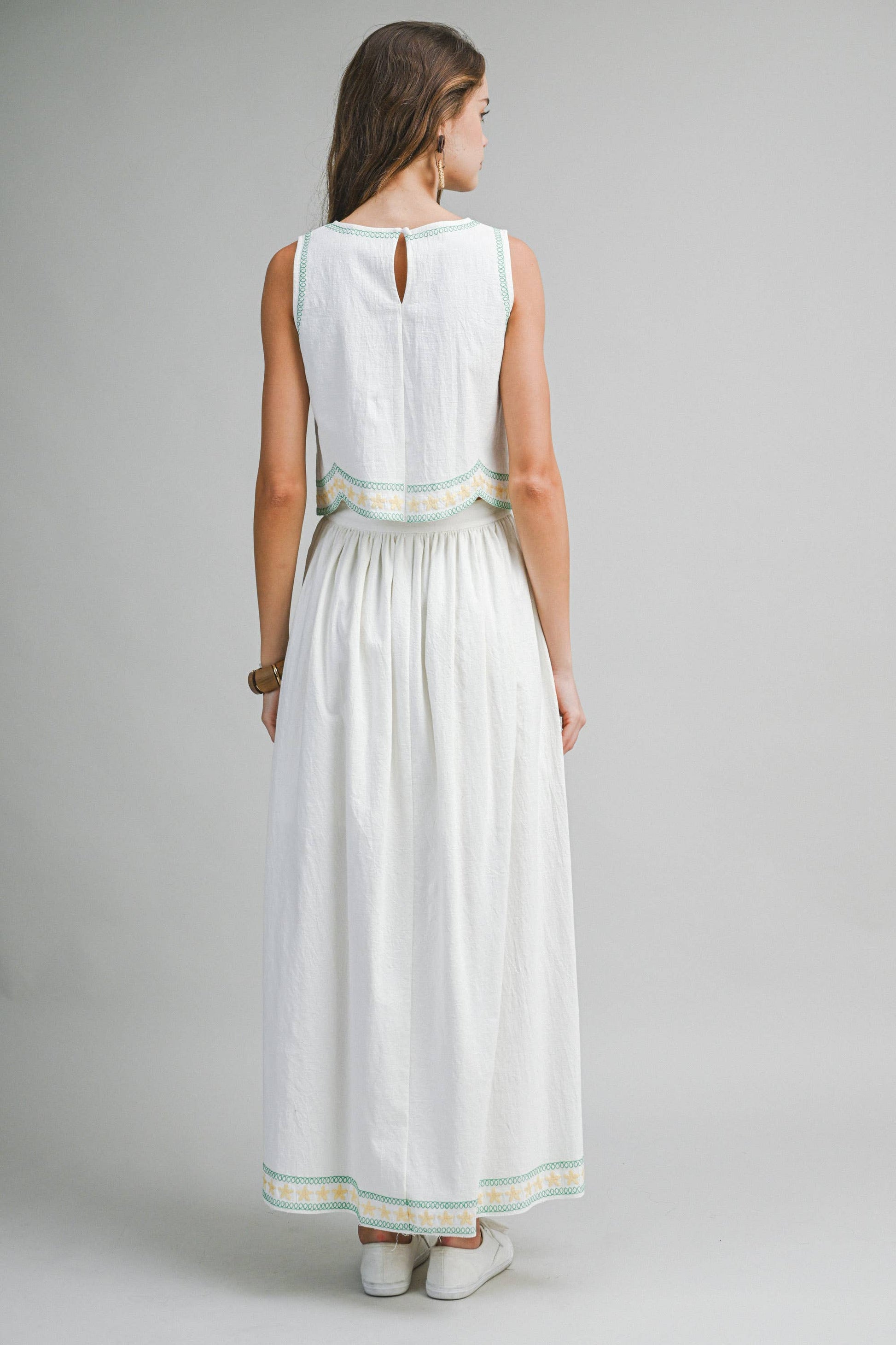 Woman wearing a white dress with green trim on a gray background