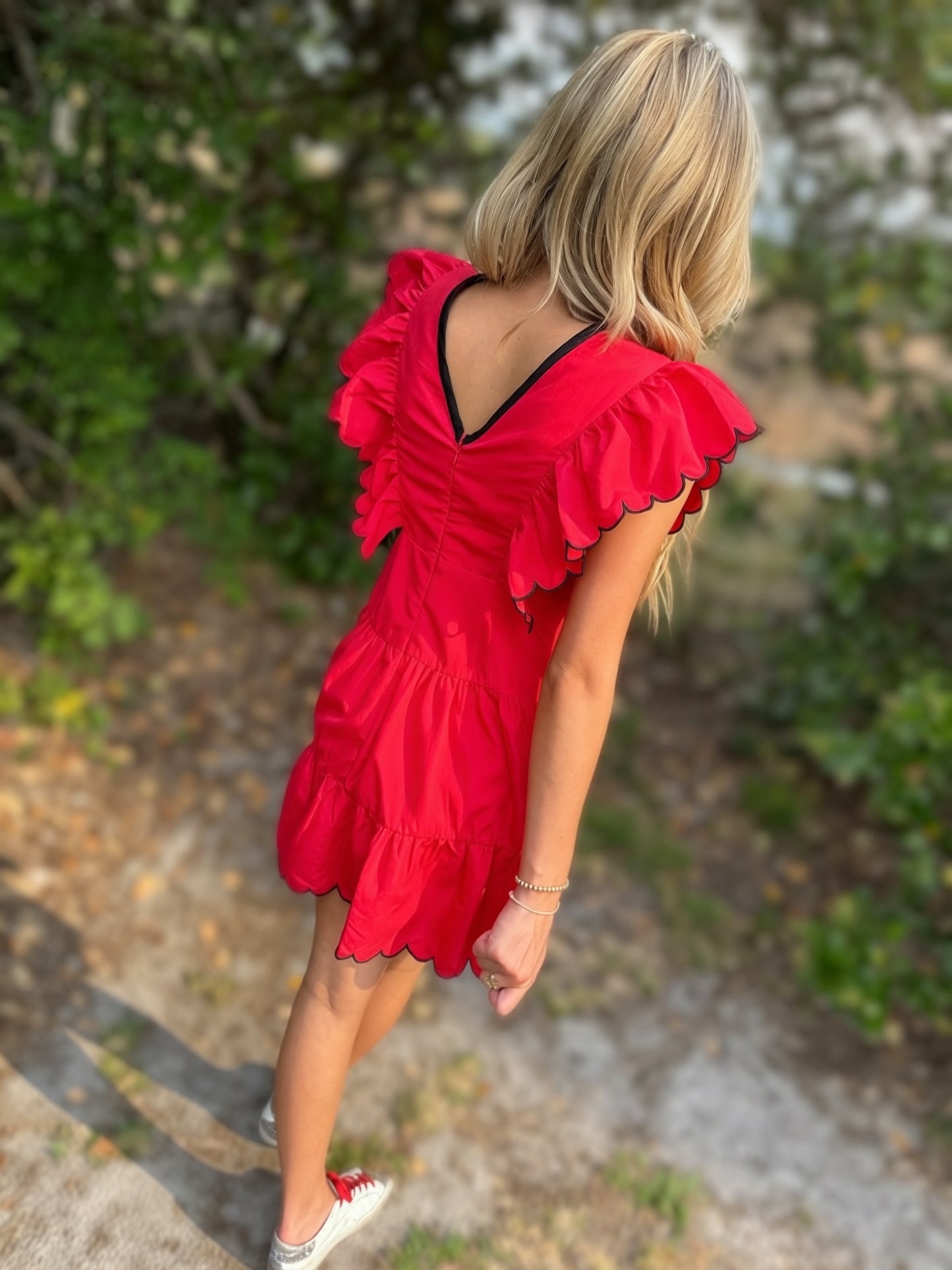 Person wearing a red dress with ruffled sleeves in an outdoor setting