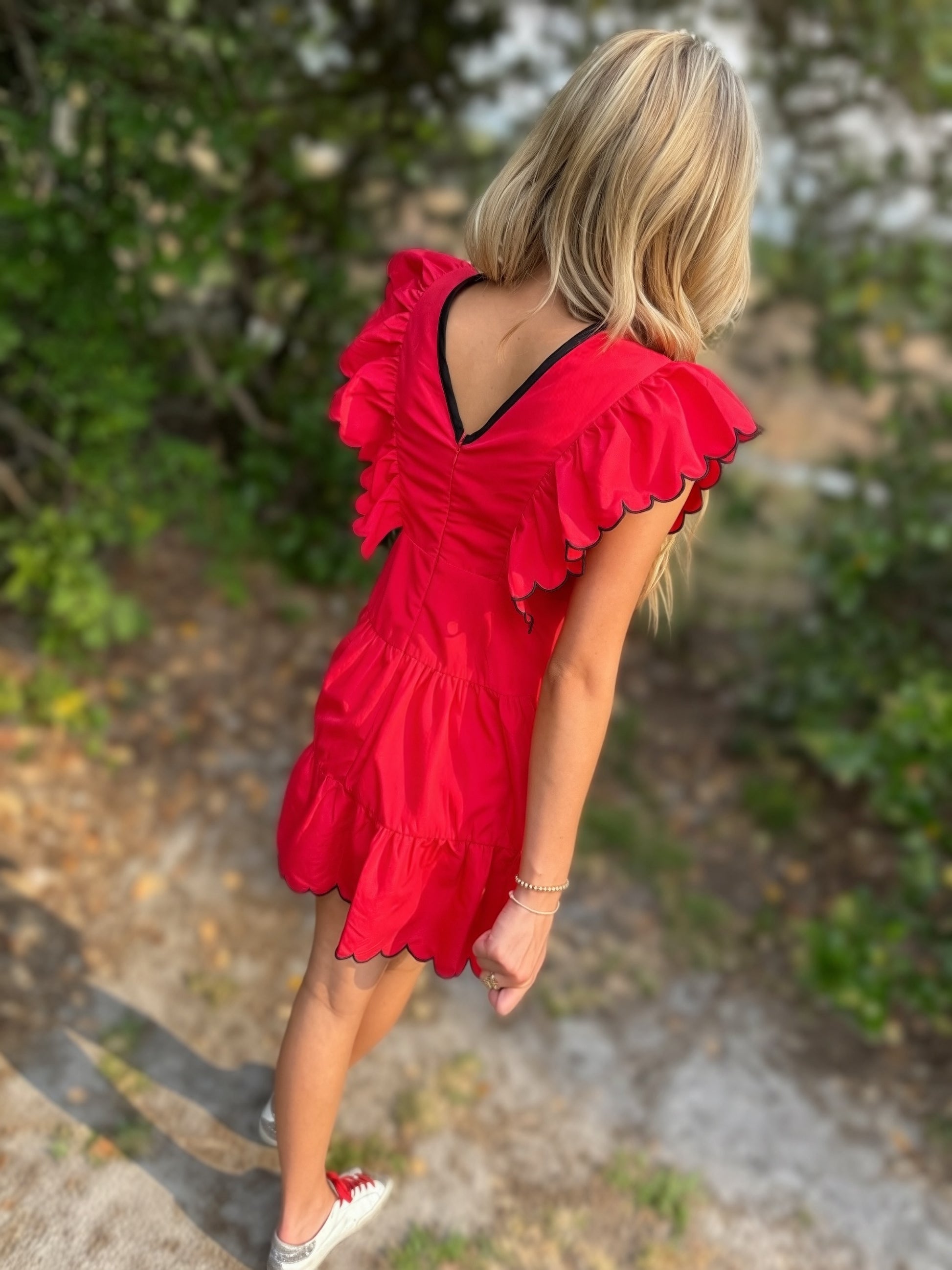 Person wearing a red dress with ruffled sleeves in an outdoor setting