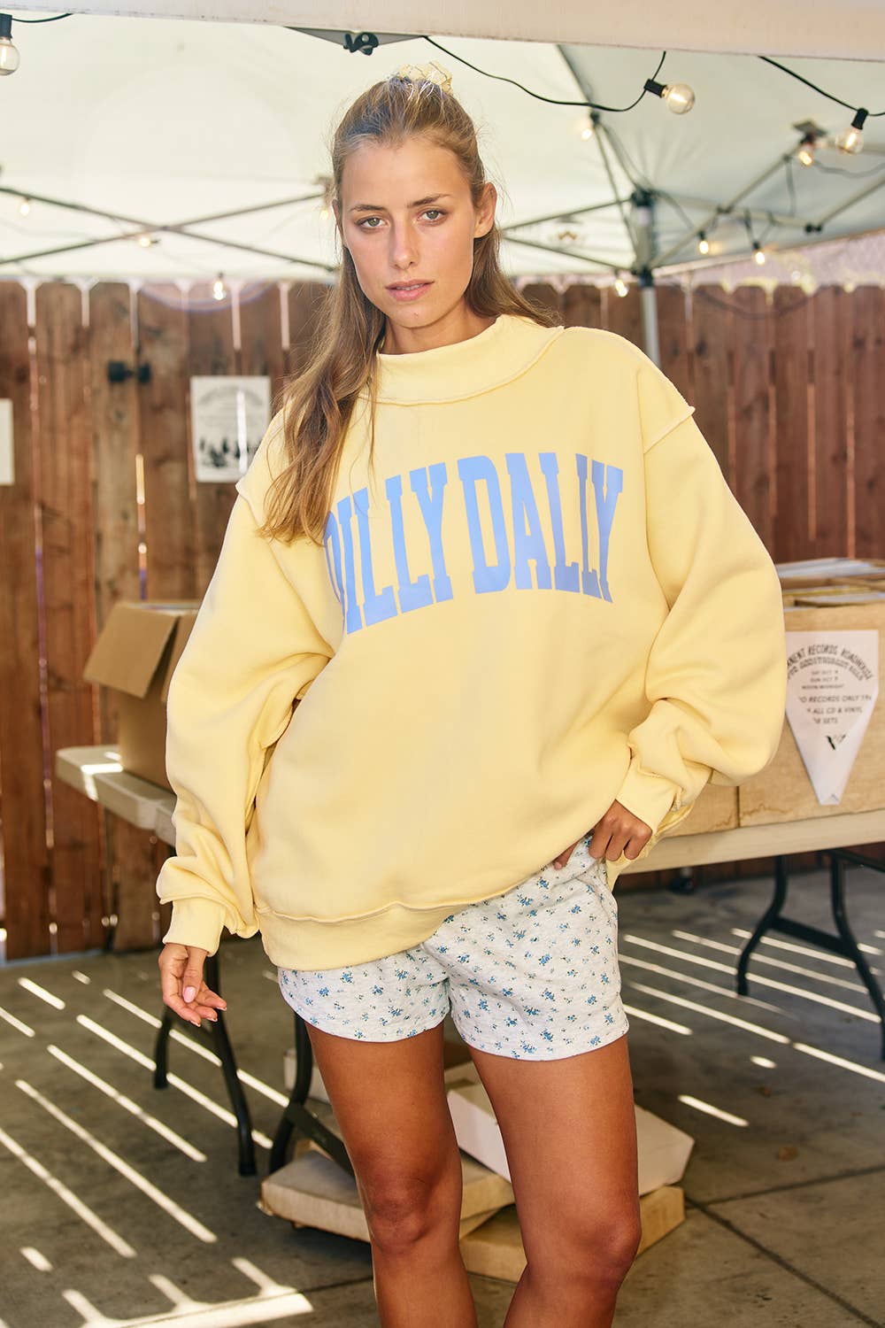 Woman wearing a yellow sweatshirt with 'Dilly Dally' 