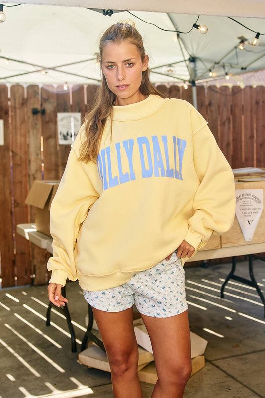 Woman wearing a yellow sweatshirt with 'Dilly Dally' 
