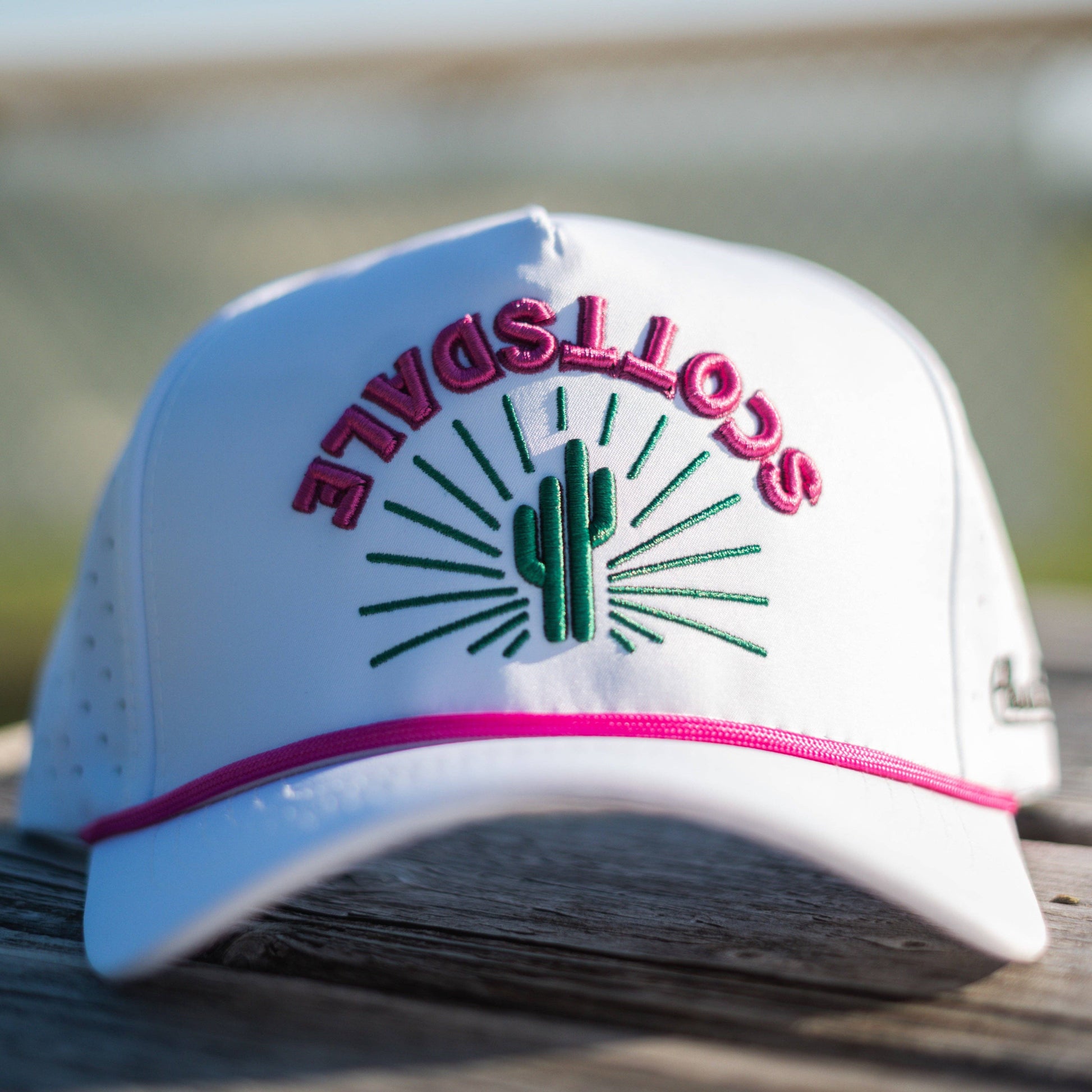 White cap with 'Scottsdale' and cactus design on a wooden surface