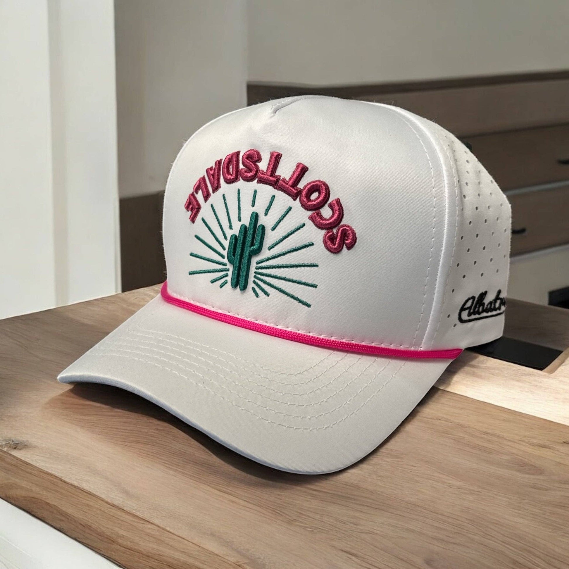 White cap with pink and green design on a wooden surface